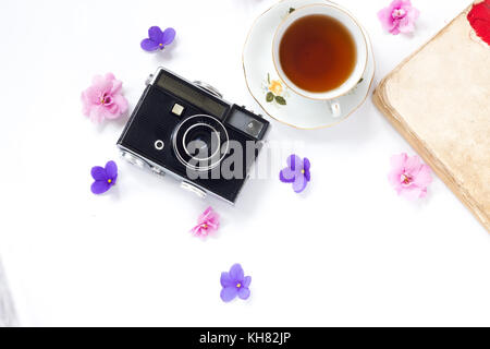 Composizione con tazza di tè, vintage fotocamera, vecchi libri su sfondo bianco vista dall'alto. Foto Stock