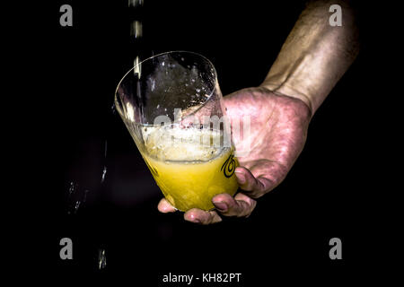 Giovane uomo spagnolo versando il sidro asturiano Foto Stock