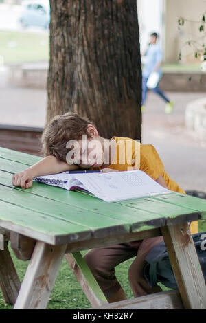 Il scolaro si è addormentato su di una cartella di lavoro con i suoi compiti Foto Stock