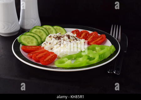 Facile colazione con paprica, pomodoro, cetriolo con ricotta e semi di lino su una piastra su un sfondo scuro mangiare sano concetto. cibo sano Foto Stock