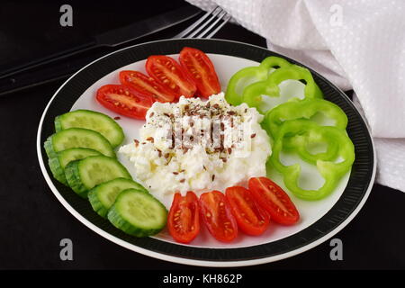 Facile colazione con paprica, pomodoro, cetriolo con ricotta e semi di lino su una piastra su un sfondo scuro mangiare sano concetto. cibo sano Foto Stock