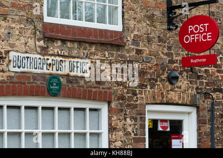 Vista esterna del piccolo villaggio rurale post office shop (chiusa oggi) con segni diversi, windows & porta - Bugthorpe, nello Yorkshire, Inghilterra, Regno Unito. Foto Stock