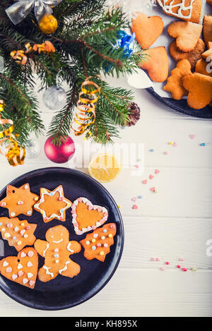 Natale in casa gingerbread cookies sul bianco tavolo in legno, natale concetto di sfondo. il processo di decorazione con crema di meringa. messa a fuoco selettiva. spazio per il testo, vista dall'alto Foto Stock