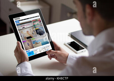 Bussinessman in ufficio tenendo un tablet mostra online magazine sito. Tutti i grafici dello schermo sono costituiti. Foto Stock
