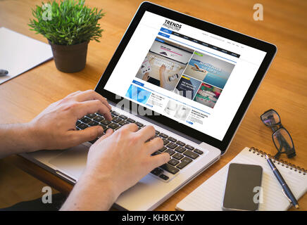 Navigare on-line concept. close-up vista dall'alto di un uomo tendenze di lettura rivista sul laptop. Tutti i grafici dello schermo sono costituiti. Foto Stock