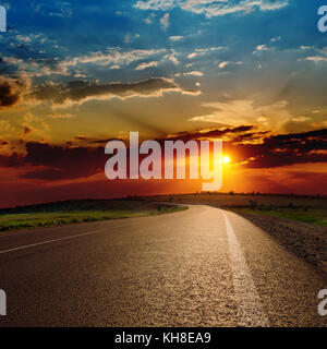 Rosso tramonto spettacolare su strada asfaltata Foto Stock