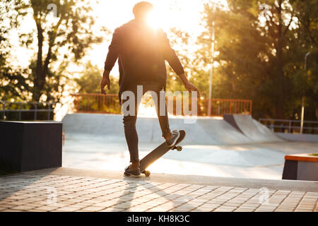 African guidatore di skateboard pattinaggio su un calcestruzzo rampa di skateboard a skate park Foto Stock