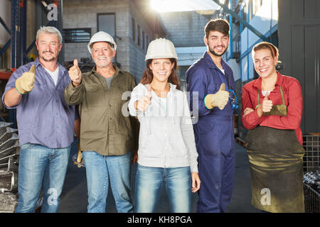 Team di operai con il pollice in alto come motivazione Foto Stock