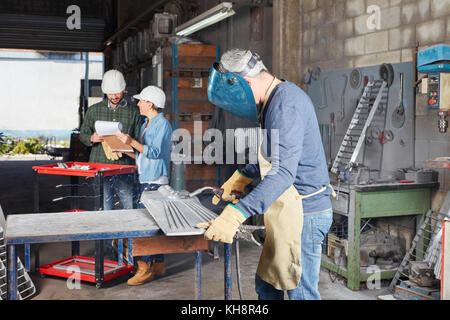 Saldatore o metallurgo con abbigliamento protettivo in officina Foto Stock