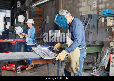 Saldatore come lavoratore lavora con acciaio in fabbrica di metallo Foto Stock