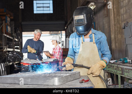 Lavoratore di saldatura o collare blu lavoratore con abbigliamento protettivo in officina Foto Stock