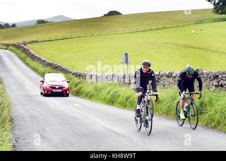 I ciclisti escursioni in bicicletta in una attività sportive lungo una strada di campagna nei pressi di Eston, Yorkshire Dales REGNO UNITO Foto Stock