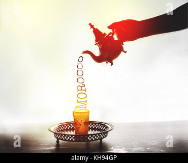 Una mano che serve tè marocchino in forma di lettere Foto Stock