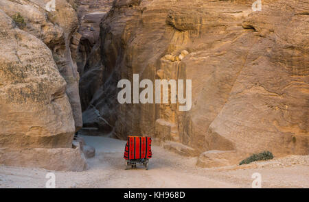 Un cavallo e carrozza di prendere i turisti attraverso l'ingresso per le strette arenaria rosa Siq gorge, Petra, all'inizio. La luce del mattino, Giordania, Medio Oriente Foto Stock