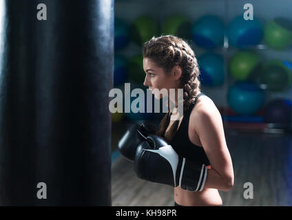 Giovane combattente ragazza boxer in formazione con pesanti sacco da boxe Foto Stock