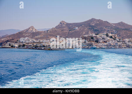 Un sentiero di bianco schiumoso e aqua acqua porta l'occhio per i bianchi edifici della città di hora impostata al di sotto della montagne aride sull isola di Naxos, Grecia. Foto Stock