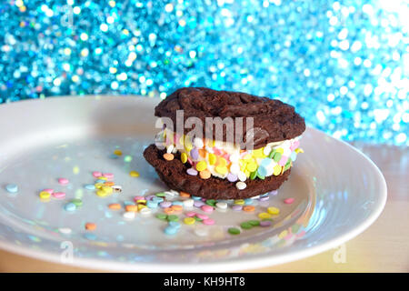 Panino gelato con biscotti al cioccolato e arcobaleno con sfondo scintillante Foto Stock