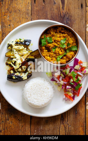 Pasto indiano con lenticchie rosse - curry masoor dal, dahi baingan, riso e insalata mista Foto Stock