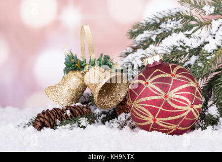 Rosso e oro palla di Natale con evergreen banco, campane e cono di pino sulla neve Foto Stock