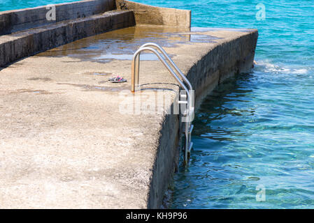 Pantofole rosa sul molo vicino al mare Foto Stock