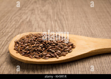 Linum usitatissimum è il nome scientifico di marrone semi di lino. Noto anche come olio di semi di lino, lino e lino comune. grani in cucchiaio di legno. rustica. Foto Stock