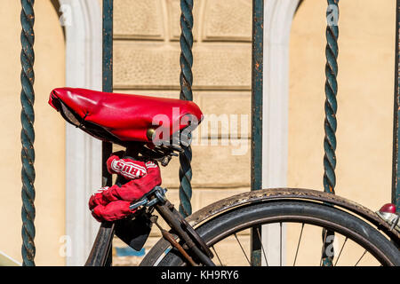 Bologna, Italia home di fabbrica della Ducati di Borgo Panigale e la marca è ovunque. Qui un ciclo ha un sedile Rosso coperchio e concatenato a un recinto. Foto Stock