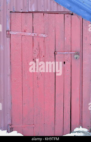 Il lucchetto chiuso la porta di legno di rosa dipinto rorbu o capanna di pesca con blu con lamiera grecata in acciaio tetto nel villaggio di pescatori di eggum-nord sh Foto Stock