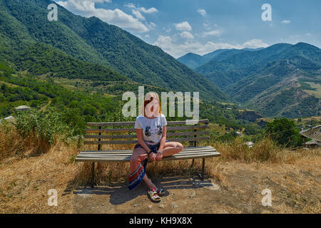 Haghpat monastero, Armenia - 01 agosto 2017: giovane donna su una panchina nei pressi di haghpat monastero di Armenia con le montagne sullo sfondo Foto Stock