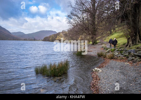 Coppia matura camminando lungo il litorale a Buttermere su un autunno giorno di novembre, Parco Nazionale del Distretto dei Laghi, Cumbria, England Regno Unito Foto Stock