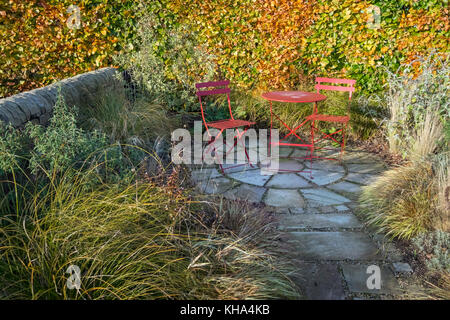 Piccolo giardino patio con pavimentazione in lastre e tavolo da pranzo e sedie, autunno, England, Regno Unito Foto Stock