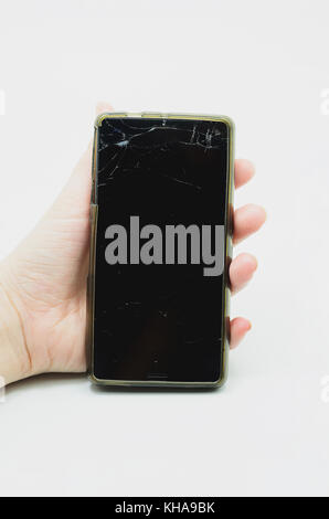 Mano che tiene uno smartphone con il vetro dello schermo rotto. Touch screen rotto. Foto Stock