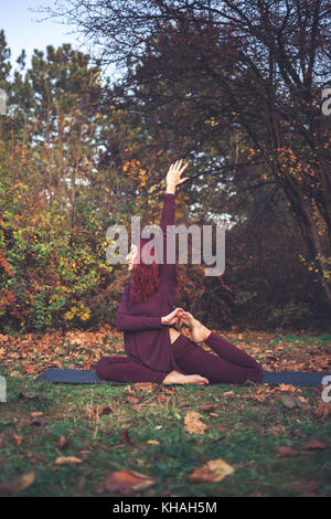 Ragazza di una luminosa giornata autunnale a praticare yoga all'aperto, facendo una variazione su uno zampe piccioni King (eka pada rajakapotasana) Foto Stock