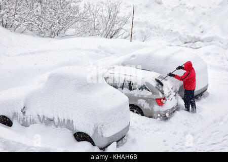 Giovane uomo attraente spazzolando la neve fuori la sua auto in una fredda giornata invernale Foto Stock