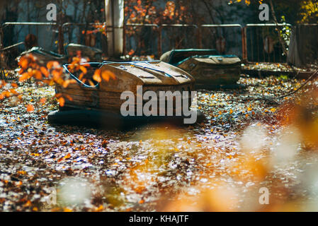 Un dimenticata bumper car si trova tra foglie di autunno nella famigerata abbandonato il parco a tema pripjat, nei pressi di Chernobyl in Ucraina Foto Stock