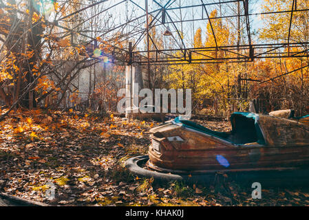 Un dimenticata bumper car si trova tra foglie di autunno nella famigerata abbandonato il parco a tema pripjat, nei pressi di Chernobyl in Ucraina Foto Stock