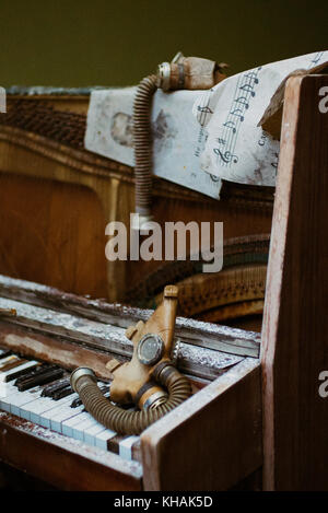Due bambini maschere di gas giacciono sparsi su un esposto e rotture di pianoforte all'interno di una scuola abbandonata, Chernobyl, in Ucraina Foto Stock