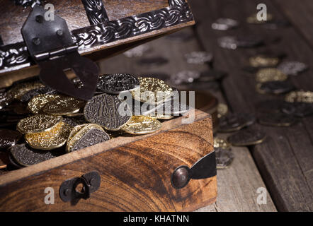 Primo piano di un piccolo scrigno pieno di monete d oro e d argento Foto Stock