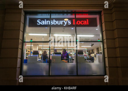 Guardando attraverso la finestra di un Sainsburys locale con self service casse late night shopping in Bath Regno Unito Foto Stock