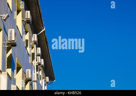 Edificio per uffici con un sacco di condizionatori d'aria su di una parete contro un cielo blu Foto Stock