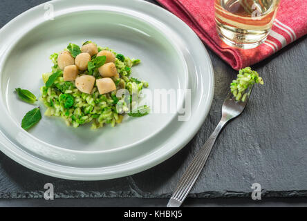 Capesante su coniate pea risotto guarnito con menta fresca Foto Stock