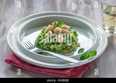 Capesante su coniate pea risotto guarnito con menta fresca Foto Stock