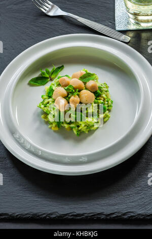 Capesante su coniate pea risotto guarnito con menta fresca Foto Stock