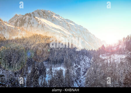 Colorful sunset in snowy winter mountains and woodland. Hintersteiner Tal, Allgau, Bavaria, Germany. Foto Stock
