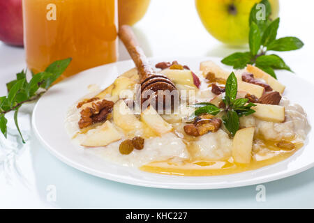 Latte dolce di farina di avena con mele, noci e miele su sfondo bianco Foto Stock