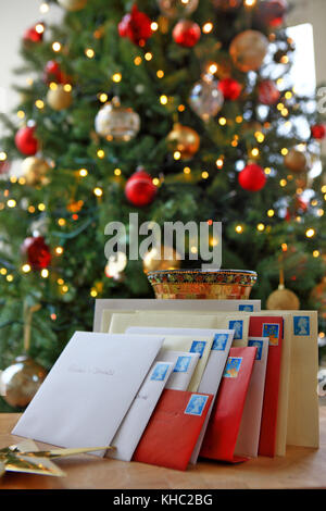 Pila di carte di Natale pronti per la pubblicazione nella parte anteriore di un albero di natale Foto Stock