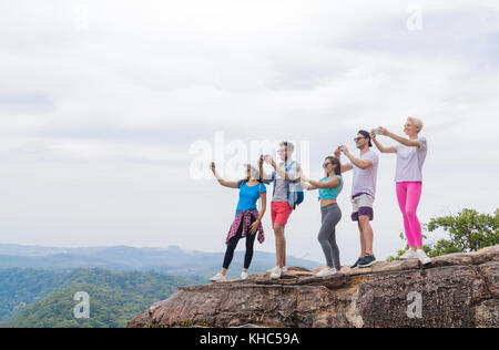 Gruppo turistico con zaino scattare una fotografia di paesaggio dalla cima della montagna sul cellulare smart phone Foto Stock