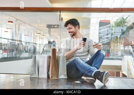 Giovane con carta di credito e lo smartphone fa acquisti su internet Foto Stock