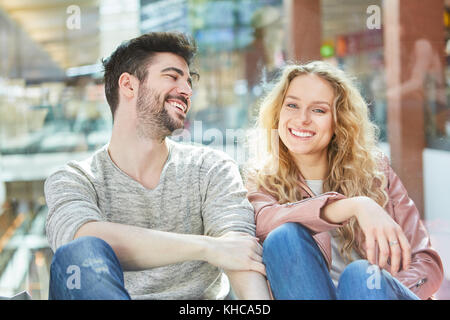 Amorosi coppia giovane felicemente seduti insieme nel centro commerciale per lo shopping Foto Stock