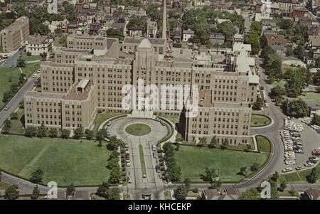 Una fotografia aerea di un Marine Hospital, la costruzione del campus medico è iniziata nel 1831 ed è stata costruita per fornire cure ai marinai dei Merchant Marines, della Guardia Costiera e di altri dipendenti federali, questa immagine cattura il grande edificio principale che ha sezioni alte sia cinque che sette piani, inclusi anche altri edifici nel vasto campus e il quartiere residenziale nella zona circostante, Staten Island, New York, 1960. Dalla New York Public Library. Foto Stock