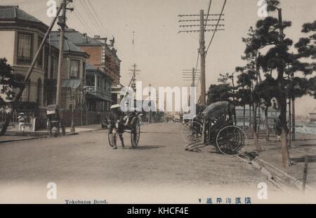 Una foto da cartolina di una vecchia strada giapponese con tre risciò (un vecchio modo di trasporto), con un risciò che viene tirato da un uomo e gli altri due parcheggiati sul lato della strada, Yokohama, Giappone, 1900. Dalla Biblioteca pubblica di New York. Foto Stock